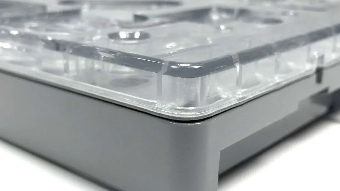 A clear moulded cover welded to a grey polymer housing around its full perimeter.