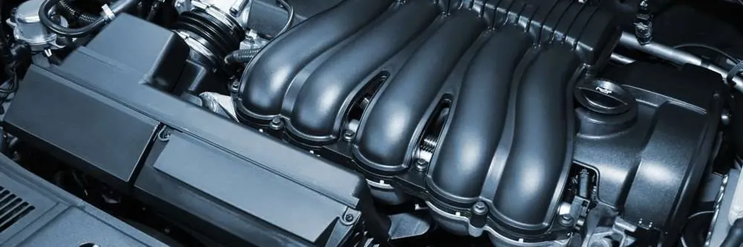 The engine bay of a passenger vehicle, intake manifold and covers in view.