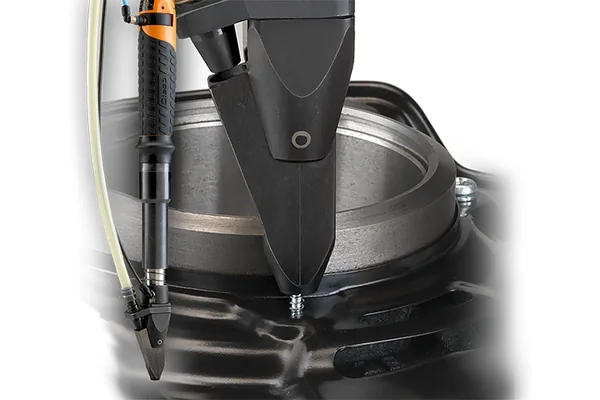 A fastener driving spindle positioned over a cast metal housing, its screw feed line attached.