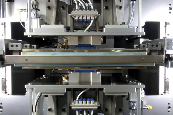 The heated platen of a hot plate welding machine between its upper and lower tooling.