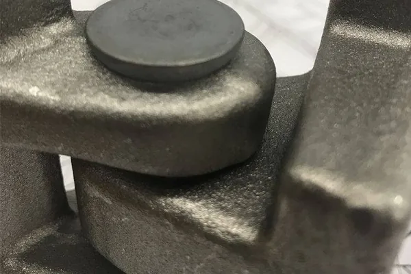 A formed rivet head clamping a joint in a cast metal bracket.